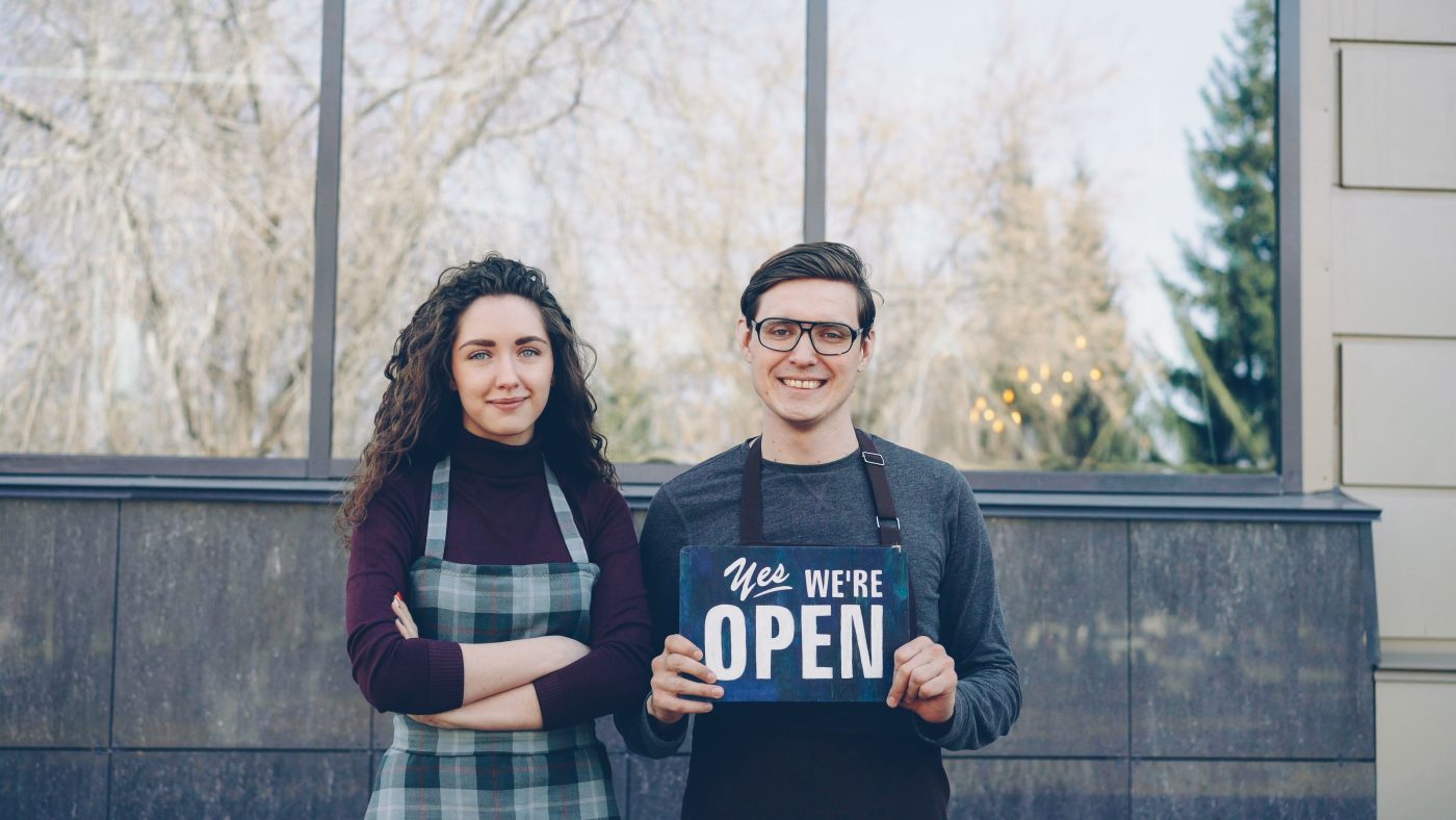 Small business owners displaying an open sign